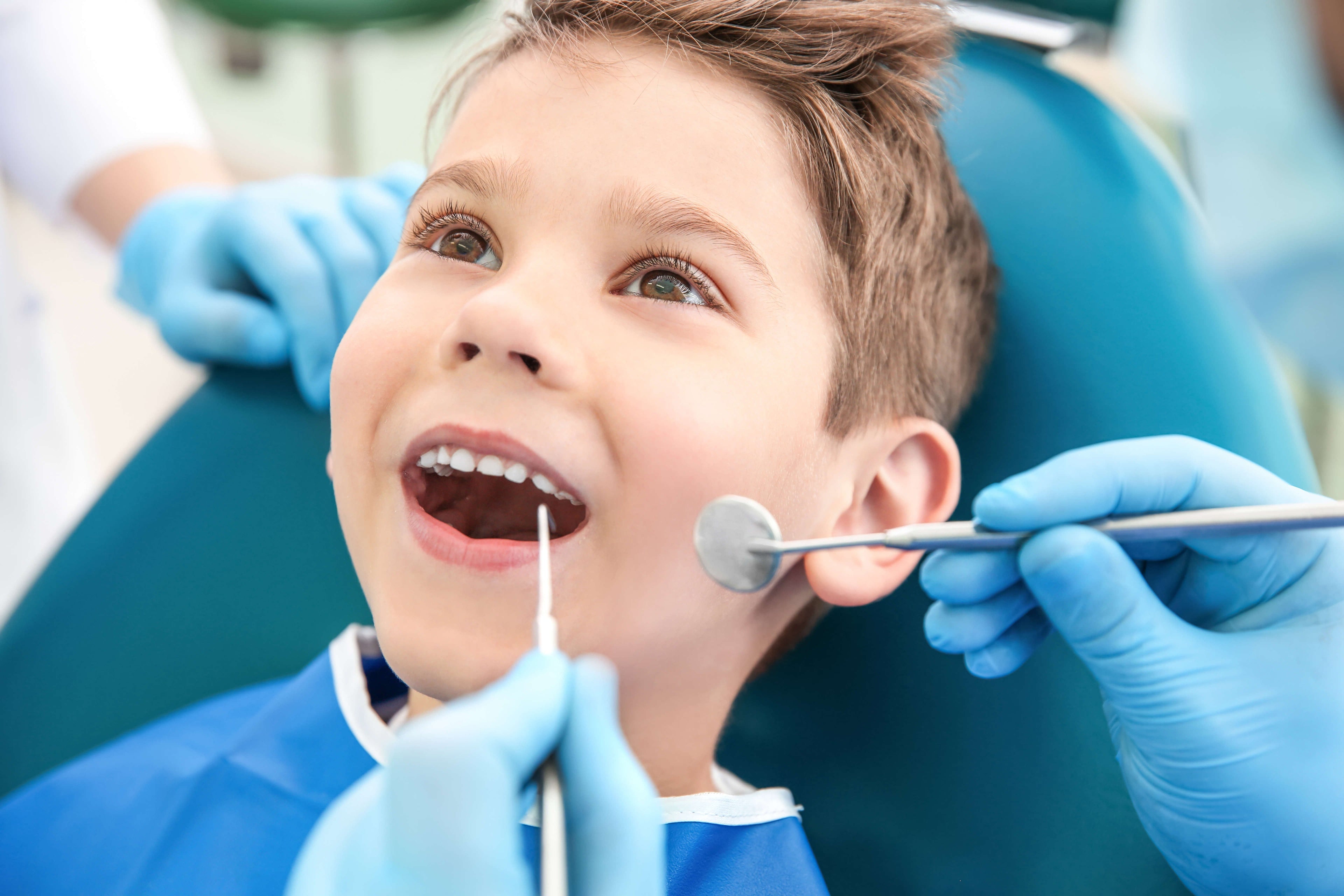 Child at a dental appointment with dental tools and gloves visible